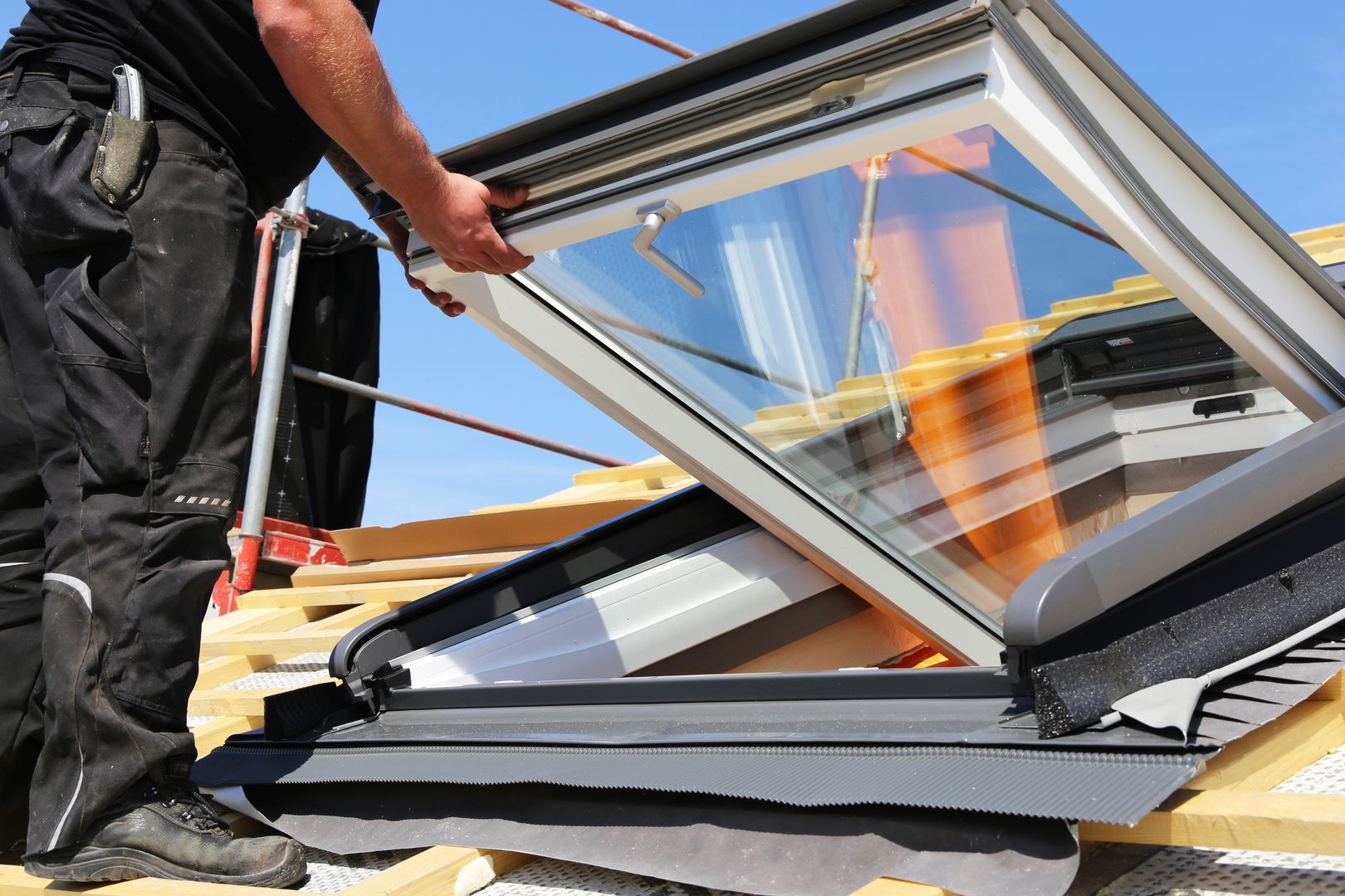 Handwerker installiert ein Dachfenster auf einer Holzunterkonstruktion.